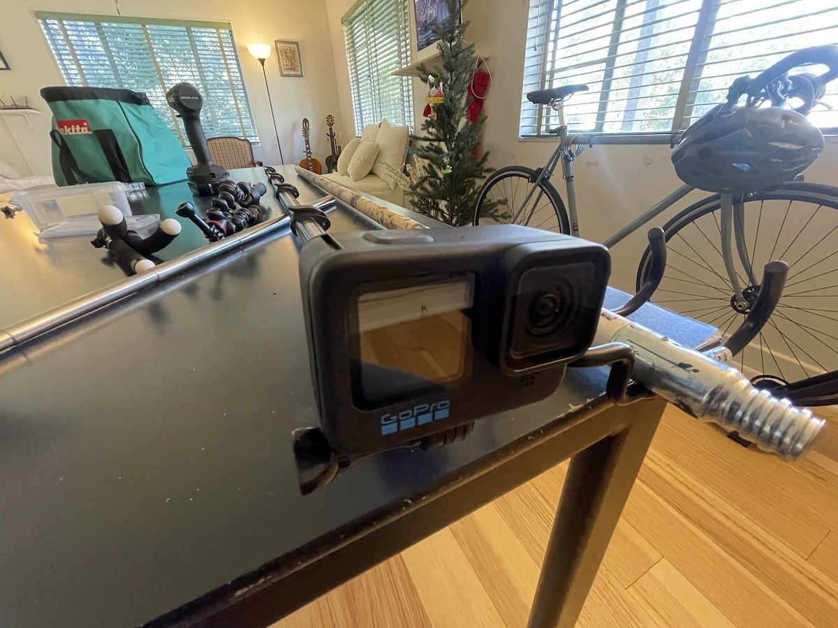 GoPro mounted to an extended monopod on a work desk, with tools and instruments in the background