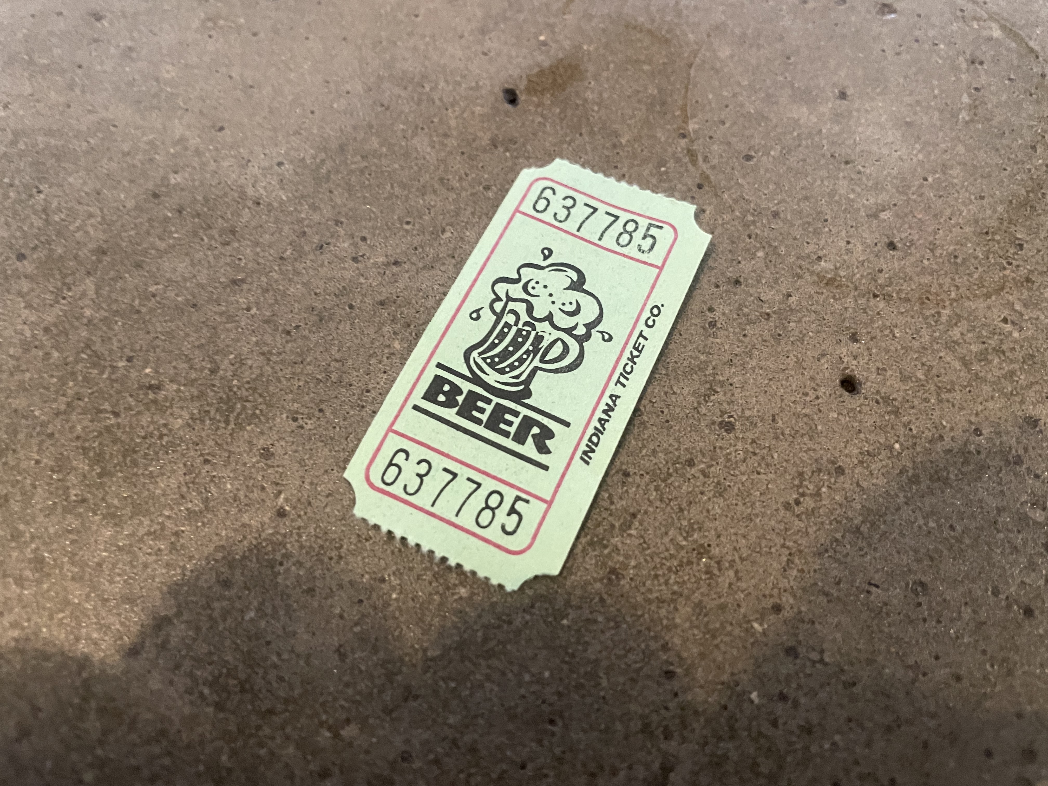 Single drink ticket on concrete floor at a brewery gathering