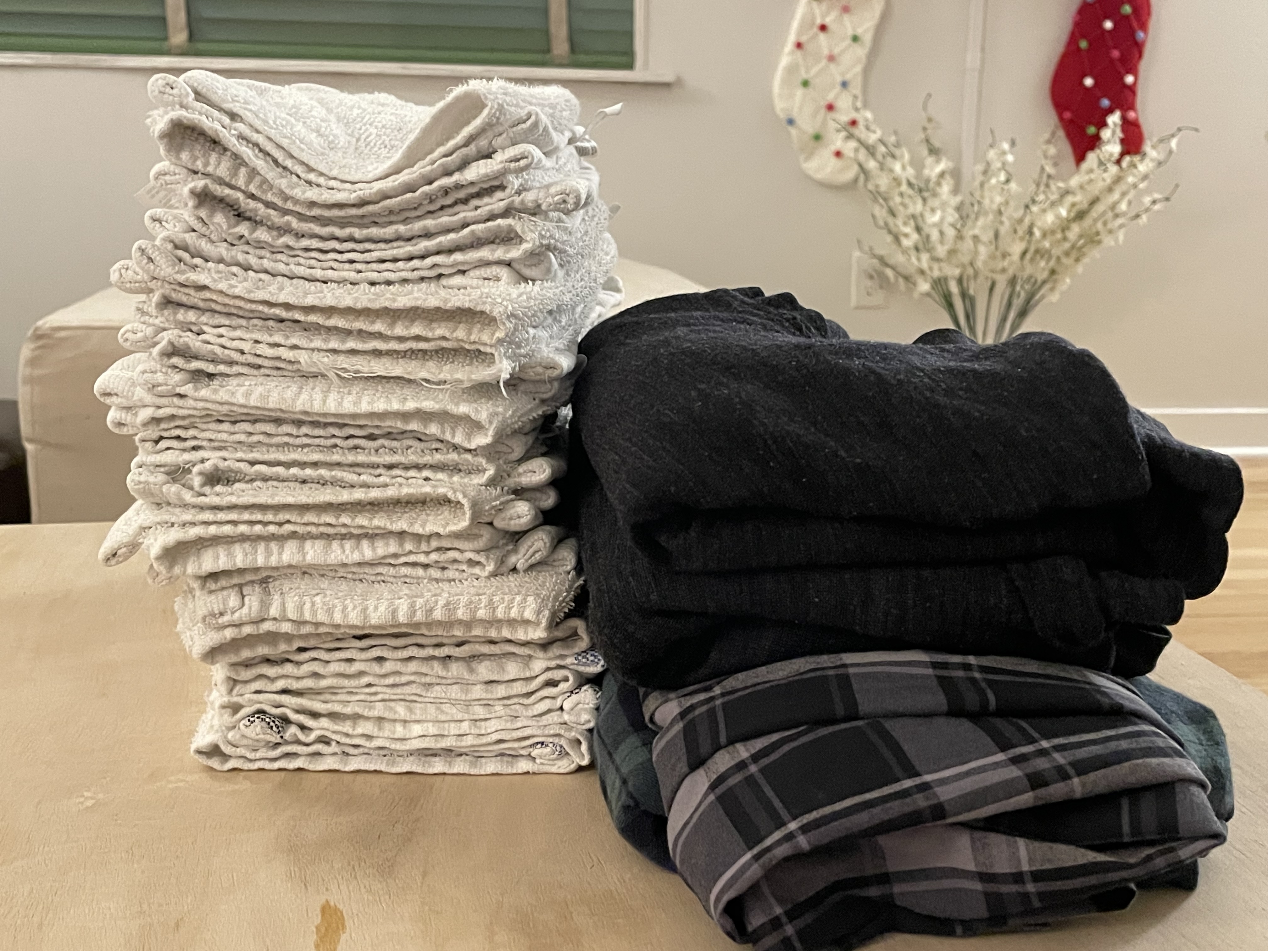 Folded laundry stacked neatly; two Christmas stockings hanging in the background